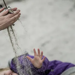 Hender som leker med sand.