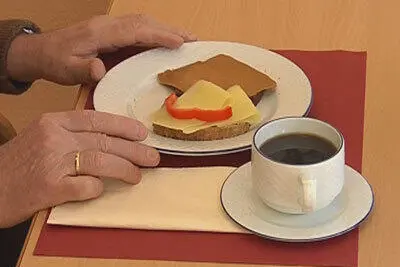 En person som holder en kopp kaffe ved siden av en tallerken med mat